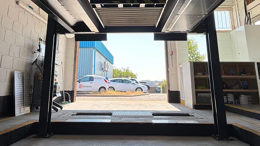 View looking out through the MOT bay doors from under a vehicle lift