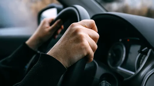 Driver's hands gripping a car steering wheel