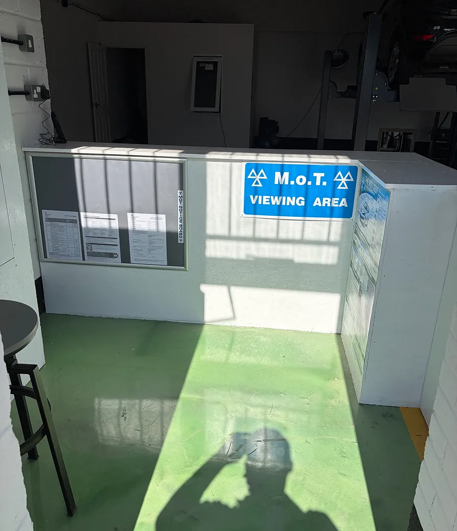 The MOT viewing area with a blue sign and notice board in the workshop reception