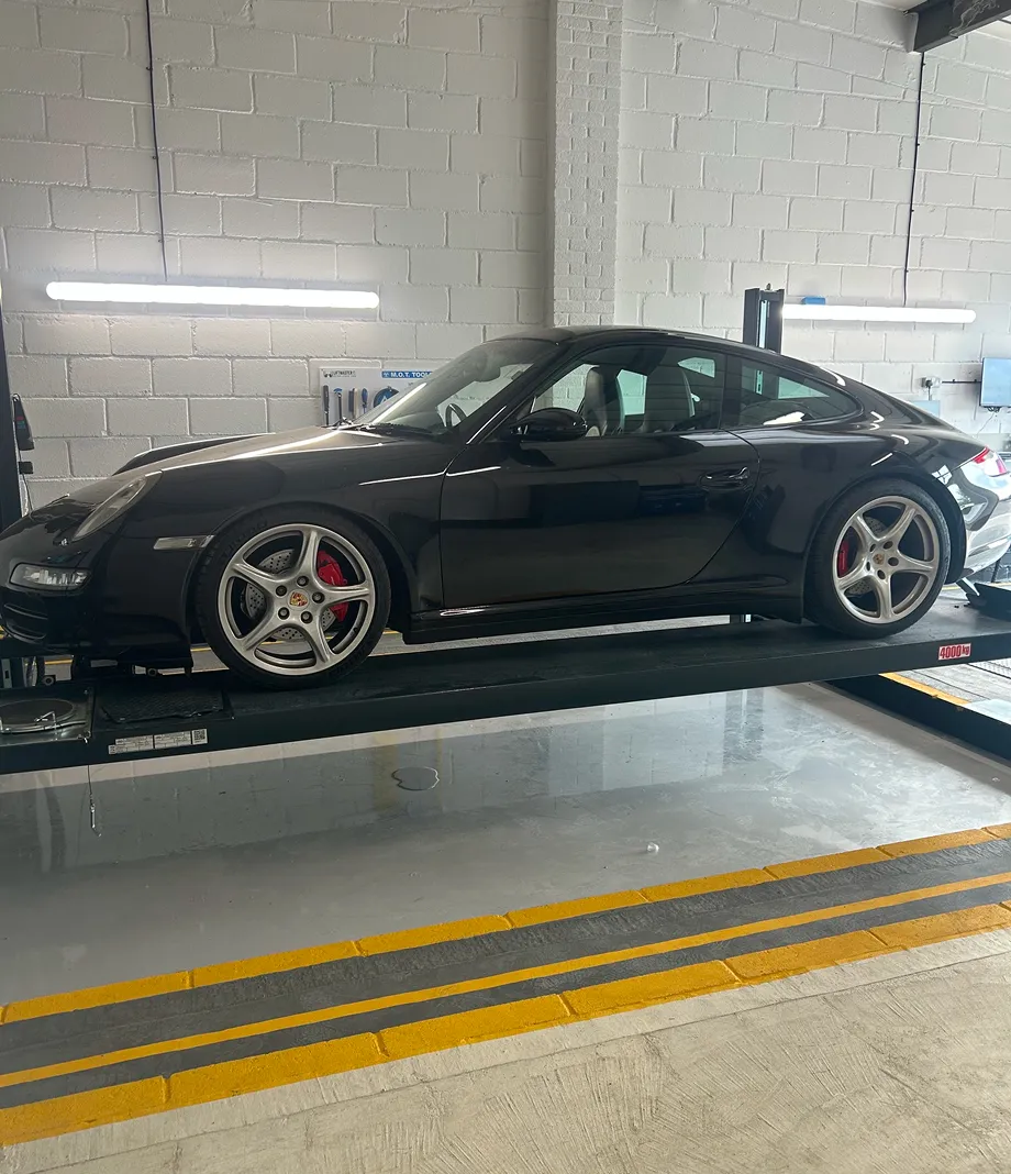 A black Porsche 911 on a four-post lift in the workshop
