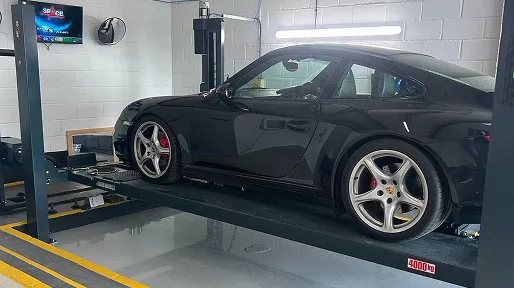 A black Porsche on a four-post lift in the workshop
